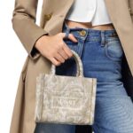 The Versace Barocco Athena Extra Small Tote Bag is an exquisite fusion of opulence, sophistication, and timeless elegance. Crafted with meticulous attention to detail, this iconic piece encapsulates the essence of the Versace brand, showcasing its signature Barocco motif and distinctive design elements. At first glance, the bag exudes a sense of luxury, boasting a striking combination of rich textures and vibrant hues. The Barocco motif, synonymous with Versace's heritage, adorns the exterior of the bag, intricately woven into the fabric with precision and finesse. Its bold and intricate patterns pay homage to classical Greek and Roman art, adding a touch of regal grandeur to the design. Constructed from premium materials of the highest quality, the tote bag is both durable and luxurious. The supple leather exterior is soft to the touch, while the gleaming gold-tone hardware adds a touch of glamour and refinement. The structured silhouette maintains its shape effortlessly, exuding an air of sophistication and poise. Practical yet stylish, the Extra Small Tote Bag is designed to cater to the modern woman's lifestyle. Despite its compact size, the interior offers ample space to accommodate essentials such as keys, phone, wallet, and makeup, making it ideal for both day-to-day use and special occasions. The interior is lined with sumptuous satin fabric, providing a luxurious backdrop for your belongings. Versatility is another hallmark of this timeless accessory. Whether carried by the top handles for a polished look or slung over the shoulder using the detachable strap for added convenience, the tote bag effortlessly transitions from day to night, complementing any ensemble with effortless sophistication. In conclusion, the Versace Barocco Athena Extra Small Tote Bag is a true masterpiece that embodies the epitome of luxury and style. With its exquisite craftsmanship, iconic design, and practical functionality, it is more than just a fashion accessory—it is a symbol of prestige, refinement, and enduring elegance.